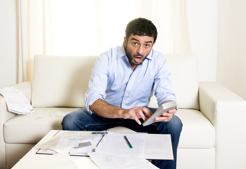 latin business man worried paying bills on couch